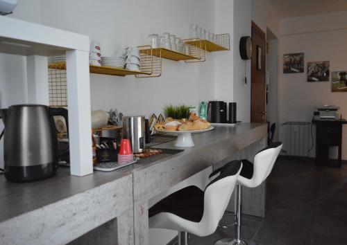 eine Küche mit einer Theke und 2 weißen Stühlen in der Unterkunft B&B SERENITY2024 in Rom