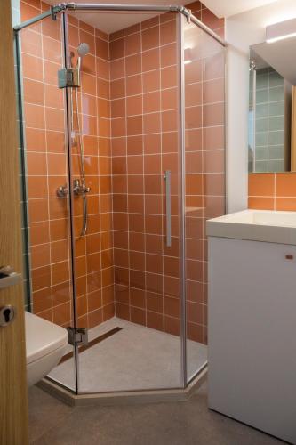 an orange tiled bathroom with a shower and a sink at The SPOT apartments - Orbi Beach Tower in Batumi