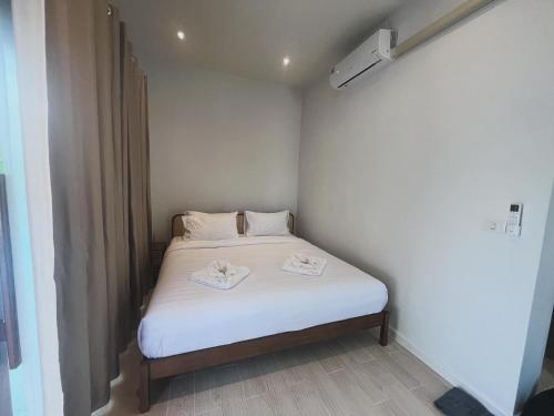 a small bedroom with a white bed with towels on it at บ้านพูลวิลล่าอุดรธานี by บ้านแสนรัก in Udon Thani
