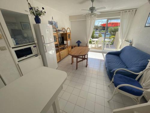 un salon avec un canapé bleu et une cuisine dans l'établissement Villa climatisée proche plage avec parking au Cap d'Agde - FR-1-723-144, au Cap d'Agde