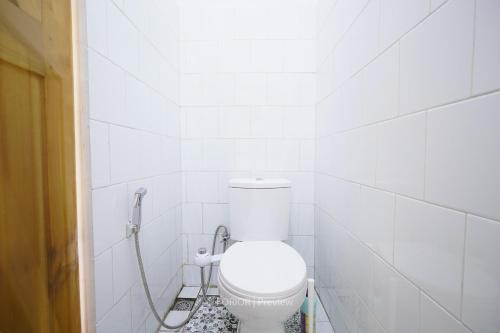 ein Bad mit einem WC in einer weiß gefliesten Wand in der Unterkunft RUMAH BIRU in Bandung
