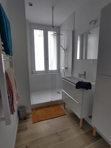 une salle de bain blanche avec un lavabo et une fenêtre dans l'établissement Appartement lumineux et spacieux 70m2 proche de tout - 3 chambres, à Nantes