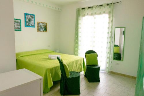 a bedroom with a green bed and two chairs at Casa Stelle Marine in Palau