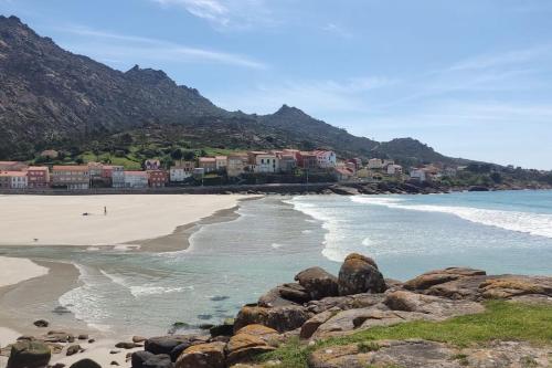 a beach with rocks and the ocean and houses at O Pindo in O Pindo