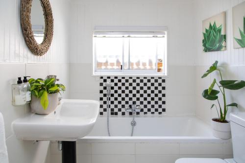 a white bathroom with a sink and a bath tub at Loddey`s Guest House - by Beach Collection in Strand