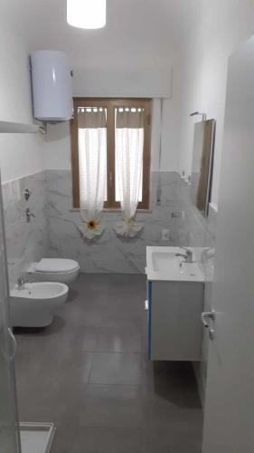a bathroom with two sinks and a toilet and two mirrors at Casa dei Mulini a vento in Trapani