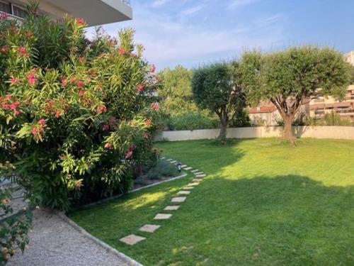 un jardin avec une pelouse et quelques buissons et arbres dans l'établissement 3 Pièces avec grand Jardin, à Cannes