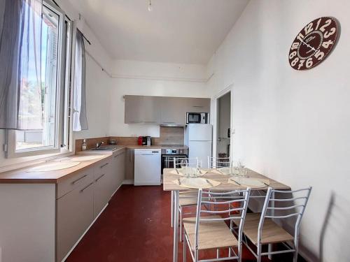 una cocina con mesa y sillas y un reloj en la pared en [L'Abbat-Jour] Le Massey • Calme • Lumineux en Tarbes