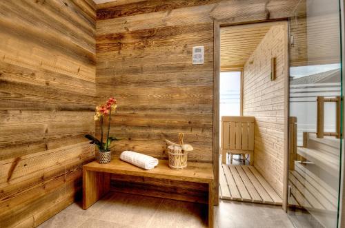 a room with a wooden wall with a bench and flowers at dasLichtenberg westside in Saalfelden am Steinernen Meer