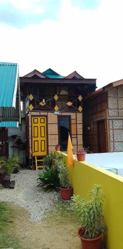 a house with a yellow door and potted plants at MLK Bamboo Beachhouse in Alegria