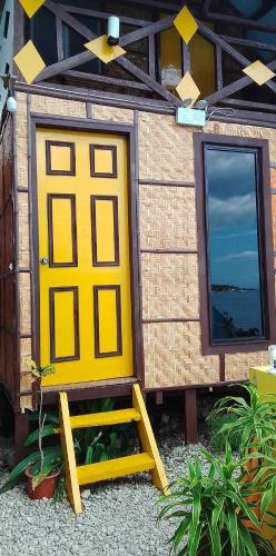 a small house with a yellow door and a ladder at MLK Bamboo Beachhouse in Alegria