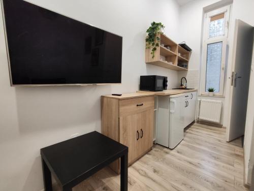 a kitchen with a large flat screen tv on a wall at Little room 7 - pokój z prywatną łazienką i aneksem in Szczecin
