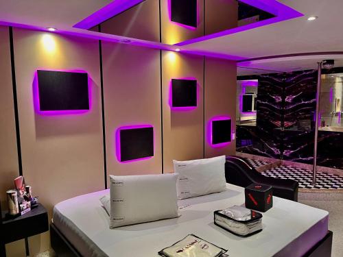 Cette chambre dispose d'un lit avec des lumières violettes sur le mur. dans l'établissement Cassino Motel 6, à Santo André
