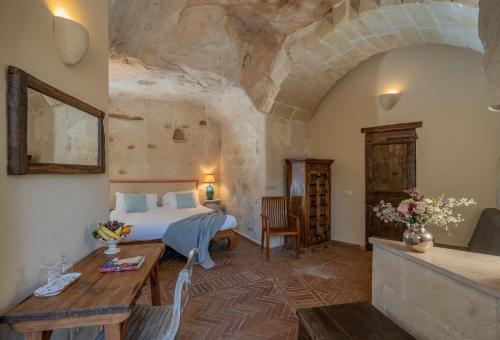 a bedroom with a bed and a table at Locanda Di San Martino Hotel & Thermae Romanae in Matera