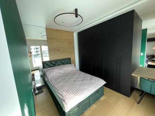 a bedroom with a bed and a black cabinet at Apartament Hańcza in Suwałki