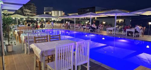 a swimming pool with tables and umbrellas at night at oasis apartment in Sarandë