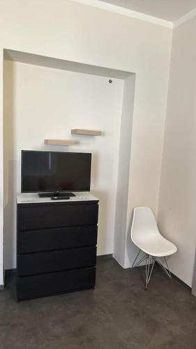 プラハにあるSelf Check-in 45m2 apartment facing tram stationの黒いドレッサーと白い椅子が備わる客室です。