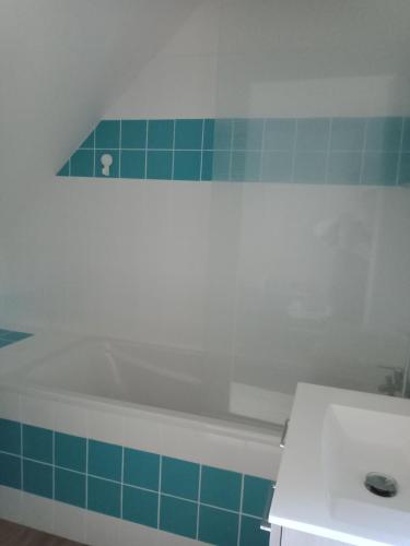 La salle de bains est pourvue d'une baignoire blanche et de carrelage bleu. dans l'établissement BINIC Studio indépendant, à Binic