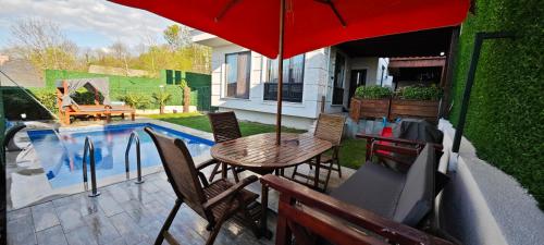 Una mesa y sillas con una sombrilla junto a una piscina. en family villas 2, en Sapanca