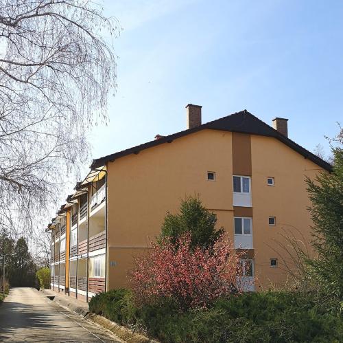 ein großes gelbes Gebäude mit einer Straße daneben in der Unterkunft Tó Apartman Gunarasfürdő in Dombóvár