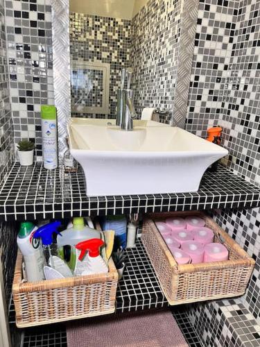 une salle de bain avec un lavabo et une étagère avec des paniers dans l'établissement Cozy haven near Paris La Defense Grande Arche, à Courbevoie