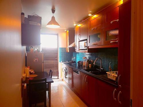 a kitchen with wooden cabinets and a sink and a refrigerator at Cozy haven near Paris La Defense Grande Arche in Courbevoie