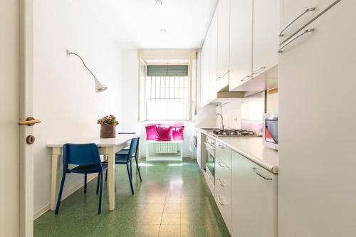 a kitchen with white cabinets and a table and chairs at Appartamento al Duomo di Parma - posto auto privato prenotabile in Parma