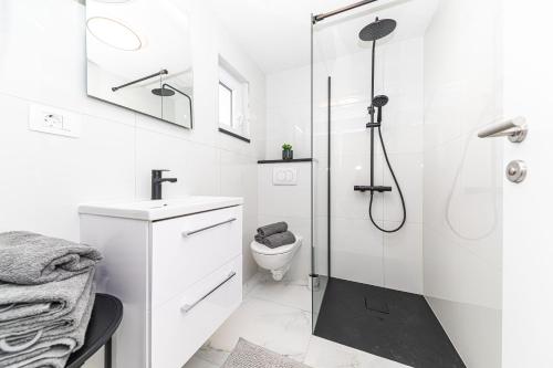 a white bathroom with a shower and a toilet at Apartman Simic in Trogir