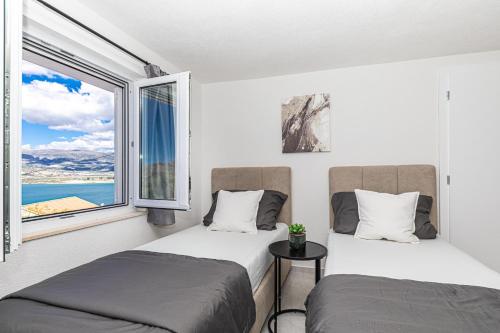 two beds in a room with a window at Apartman Simic in Trogir