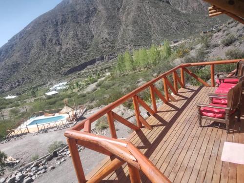 a deck with chairs and a swimming pool on a mountain at Cabaña Rincón del Sol in Potrerillos