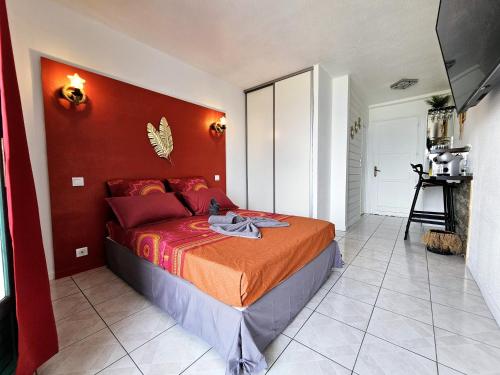 萊斯三河－勒茨的住宿－Sweet Crépuscule - Studio avec Vue Mer Imprenable & Piscine，一间卧室配有一张红色墙壁的床