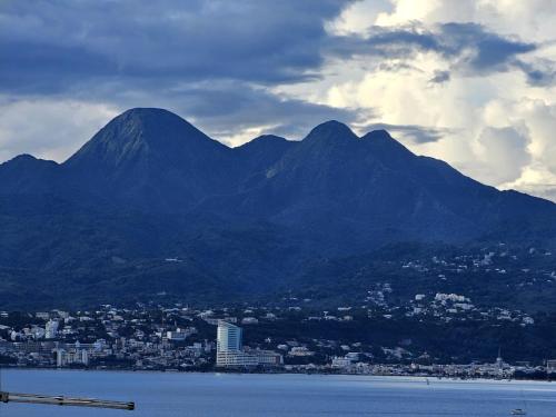 a view of a city and a mountain range at Sweet Crépuscule - Studio avec Vue Mer Imprenable & Piscine in Les Trois-Îlets