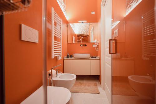 ein Badezimmer mit orangefarbenen Wänden, einem WC und einem Waschbecken in der Unterkunft La Maison di Daniela in Terlizzi