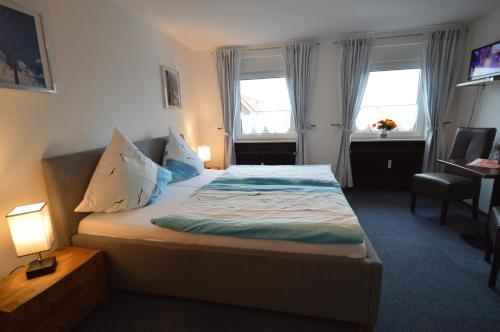 um quarto com uma cama, uma secretária e 2 janelas em Ferienwohnungen im Haus Hannover Carolinensiel em Carolinensiel
