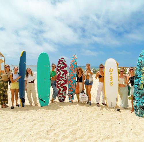 a group of people standing on the beach with surfboards at 33 Hostel in Baleal