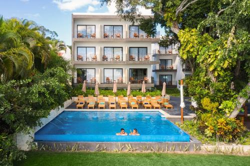 two people swimming in a pool in front of a hotel at Cristalino Lagoon Front Hotel, Restaurant & Spa in Bacalar