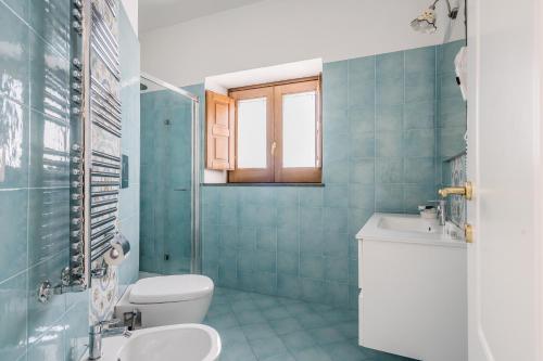 Baño de azulejos azules con aseo y lavamanos en Villa Prota, en Vico Equense