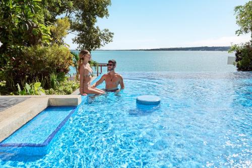 a man and a woman sitting in a swimming pool at Cristalino Lagoon Front Hotel, Restaurant & Spa in Bacalar