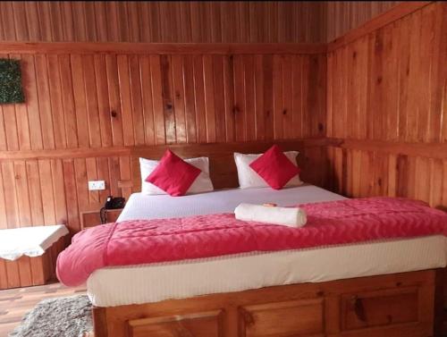 1 dormitorio con 1 cama grande con almohadas rojas en Hotel Ganpati Palace Champawat, en Champawat