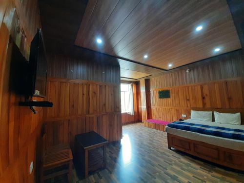 1 dormitorio con 1 cama en una habitación de madera en Hotel Ganpati Palace Champawat, en Champawat