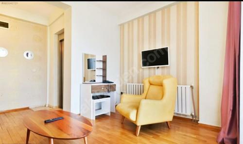 a living room with a yellow chair and a table at Omr park Suites in Istanbul
