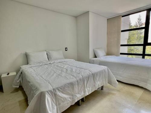 ein weißes Schlafzimmer mit 2 Betten und einem Fenster in der Unterkunft 902 luxury apartment in heart of El Poblado! in Medellín