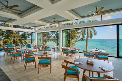 a restaurant with tables and chairs and the ocean at Cristalino Lagoon Front Hotel, Restaurant & Spa in Bacalar