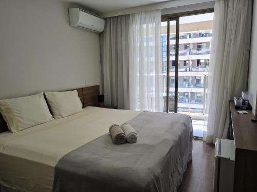 1 dormitorio con 1 cama con 2 zapatillas en Suíte Luxo Via Premiere, en Río de Janeiro
