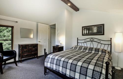 a bedroom with a bed and a chair and a window at Chalets Alpins - 17 Chemin Alpin in Stoneham