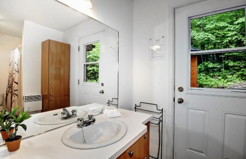 a white bathroom with two sinks and a mirror at Chalets Alpins - 17 Chemin Alpin in Stoneham