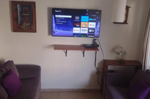 uma televisão de ecrã plano pendurada numa parede numa sala de estar em casa con vigilancia las 24hrs em Santa Cruz Tecamac