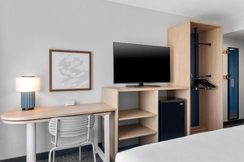 a hotel room with a desk with a television at Spark by Hilton Orlando near SeaWorld in Orlando