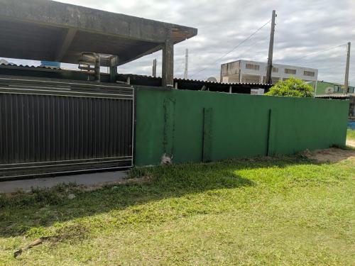 a green fence in the grass next to a building at Iguape, Jureia, Barra do Ribeira - Frente ao mar in Iguape