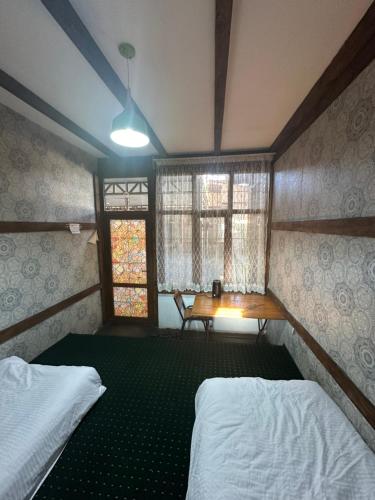 1 dormitorio con 2 camas, mesa y ventana en 阿拉木图市和平民宿, en Kalkaman